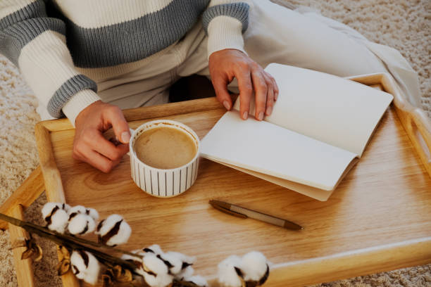 istock Cozy Writing Setup. A serene scene featuring a blank notebook, a cup of coffee, and cotton branches on a wooden tray. Perfect for themes of relaxation, planning, and home comfort 2173435228