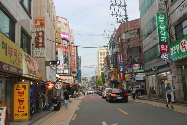Seoul, South Korea-September 19, 2024: Dusk view of people walking down major commercial avenue, lined with shops, bars, and restaurants, in downtown Jamsil, Seoul