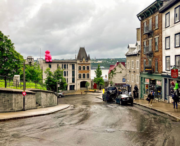 People walk along shops and cafes on the  street in Qubec City on a rainy day. The figure of \
