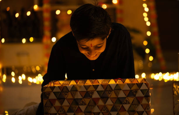 istock Excited boy opening Diwali gift in illuminated home 2173443524