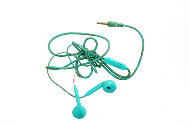 Black in ear headphones on neon green background close up. Minimal music concept. Modern earphones flat lay, top view, modern lifestyle, copy space