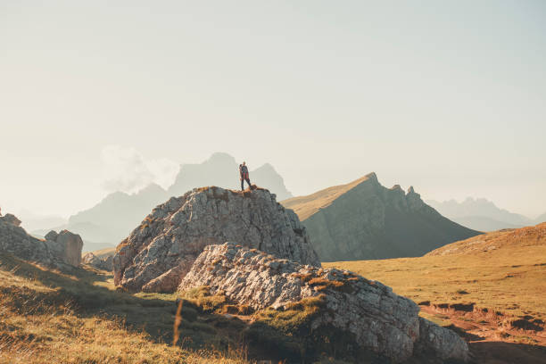 istock Young woman stands on boulder in mountain meadow 2173471063