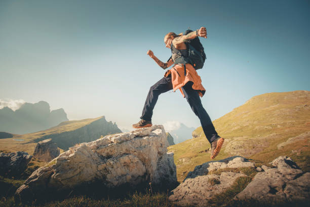 istock Young woman jumps onto boulder in mountain meadow 2173471072