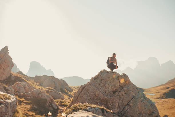istock Young woman sits on boulder in mountain meadow 2173471088
