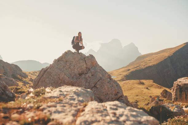 istock Young woman sits on boulder in mountain meadow 2173471093
