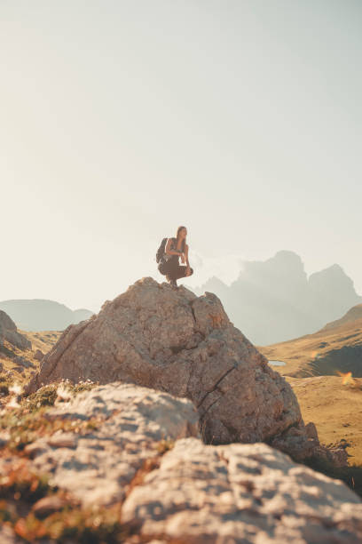 istock Young woman sits on boulder in mountain meadow 2173471094