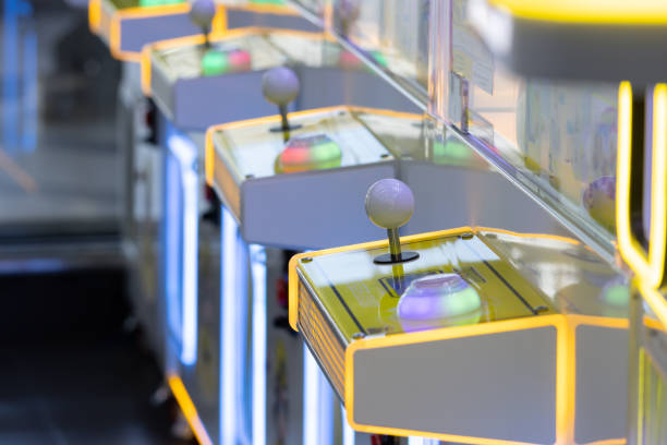 A row of arcade games with neon lights and buttons. The games are brightly lit and colorful, creating a fun and exciting atmosphere