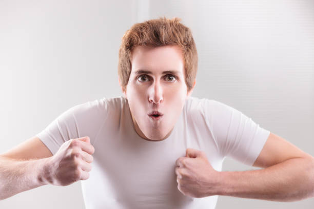 Playful imitation of a gorilla by a young man in white, humorously highlighting traditional masculine attitudes with a funny face and fists