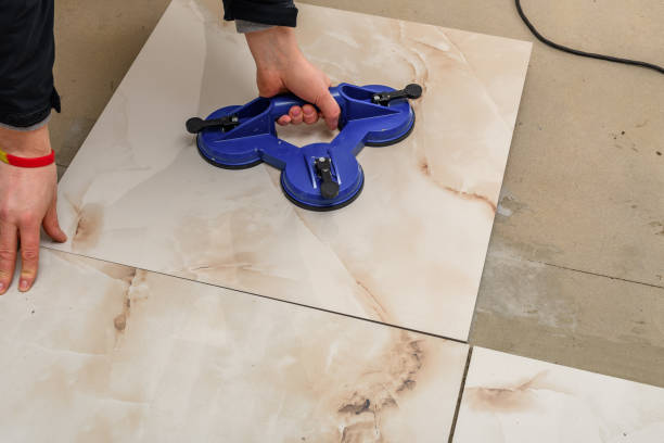 istock A foreman lays large floor tiles on a concrete floor 2173484424