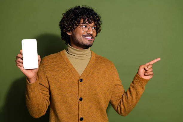 istock Photo of attractive young man hold device white screen look point empty space dressed brown clothes isolated on khaki color background 2173493196