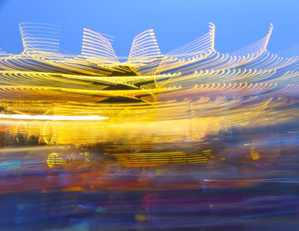 Colorful abstract blur of carnival lights in motion at night, creating swirling, vibrant patterns against a dark sky.