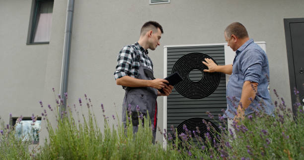 istock A technician and homeowner discuss heat pump maintenance, referencing a tablet near the unit. 2173505297