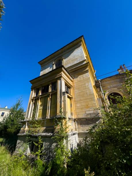 istock Sunlit Abandoned Mansion Overgrown with Vegetation under a Clear Blue Sky 2173507502