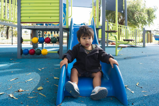 Young Toddler Having Fun on Outdoor Playground Slide