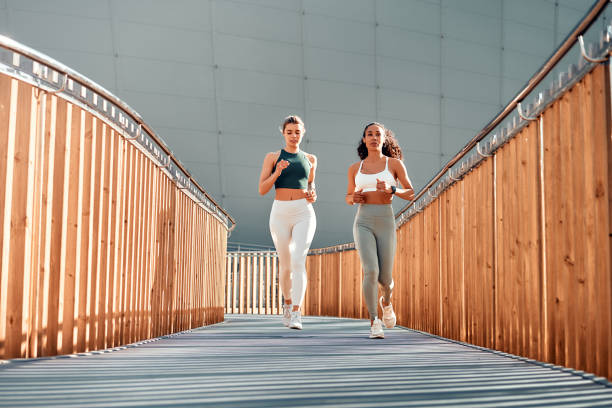 istock Focused fitness: Two women running outdoors on a modern bridge. Copy space. 2173510143