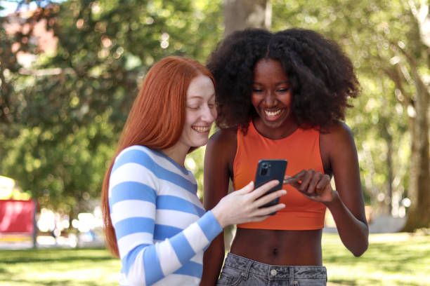istock Multiracial friendship as two women smile while looking at a smartphone 2173510848