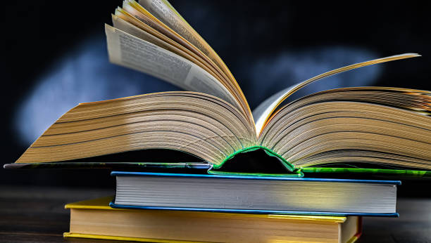 istock An open book lying on a stack of other books 2173516278