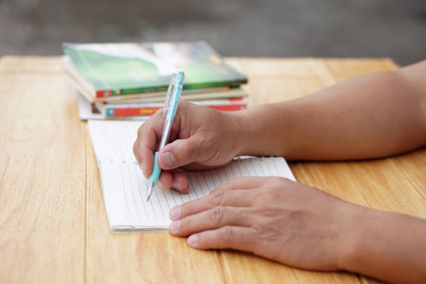 Close up hand use pen to write on paper notebook. Concept, Education. Reading and summarizing by writing idea or knowledge. Learning style. Doing homework. Prepare for test. Taking notes.