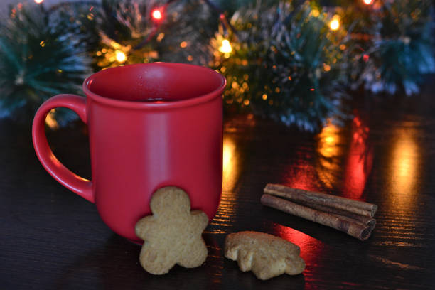 a red cup with a cookie next to a christmas tree with lights