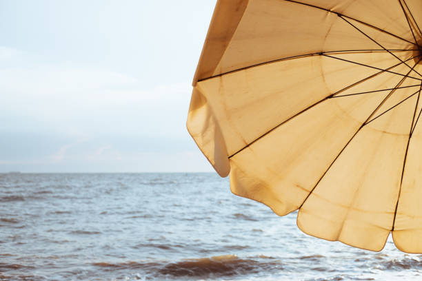 Relaxing on the beach. A yellow beach umbrellas on a sandy beach at sunset.