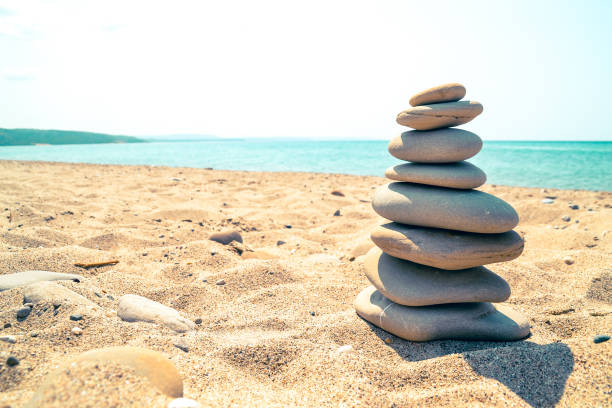 oval stones stacked on sand by the sea