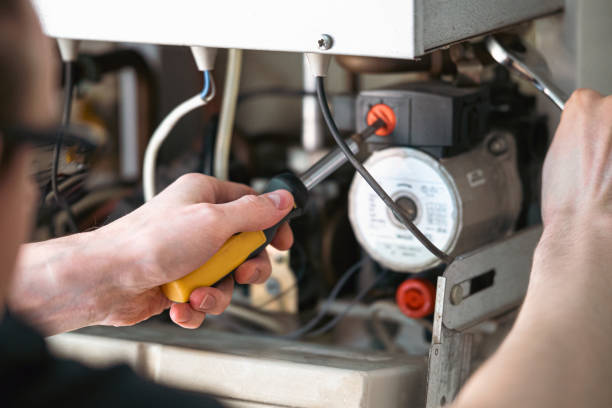 a man is repairing a water-heating boiler. - bijstellen fotos stockfoto's en -beelden