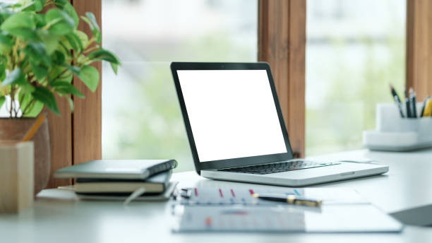istock Modern workspace featuring a laptop with a blank, white screen placed on a clean, white desk. 2173535347