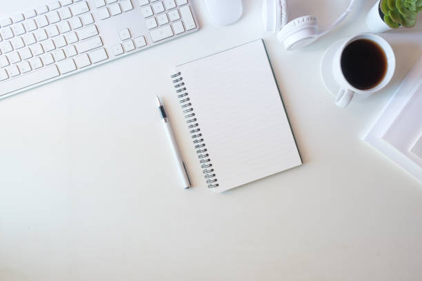 istock Minimalist workspace setup on a white desk, featuring a spiral notebook and pen at the center, ready for note-taking or journaling. 2173535406