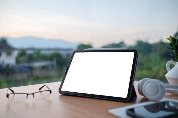 istock Minimalist workspace with blank digital tablet screen on a wooden desk, eyeglasses, wireless headphones and a cup. 2173535416