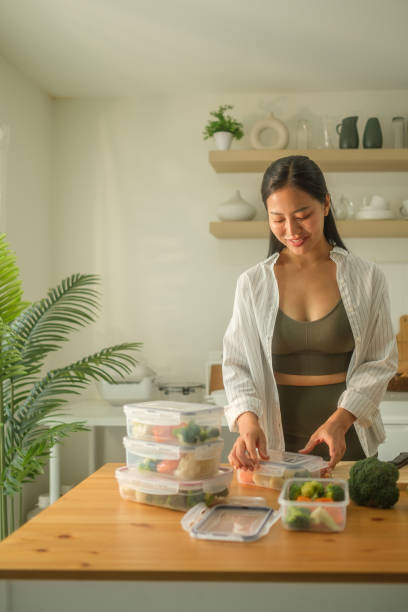 istock Young smiling sportswoman preparing containers with mixed vegetables for freezer. 2173535912