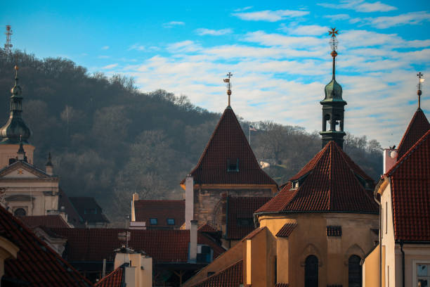 This captivating view showcases the distinctive rooftops and towers of Prague, blending historical architecture with a serene blue sky. The scene evokes a sense of timeless beauty.