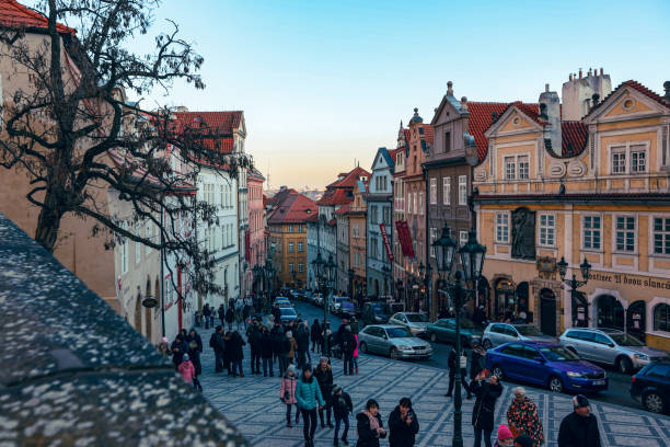 Prague, Czech Republic - December 28, 2023: Visitors stroll along a picturesque street in Prague, surrounded by historic buildings. The atmosphere is lively as people explore shops and enjoy the scenic beauty.