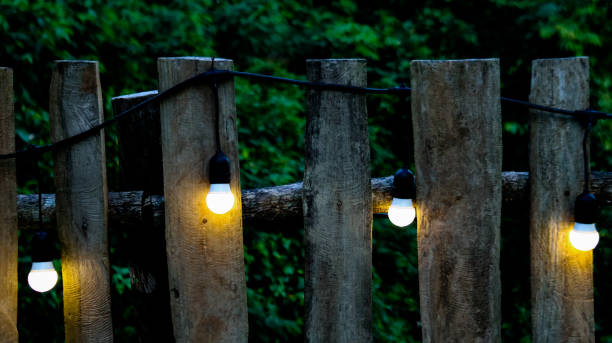 istock Small light bulbs decorated along a rustic wooden fence in a local restaurant, casting a warm, cozy glow. The soft lighting enhances the inviting atmosphere, creating a relaxed and intimate dining space. 2173554928