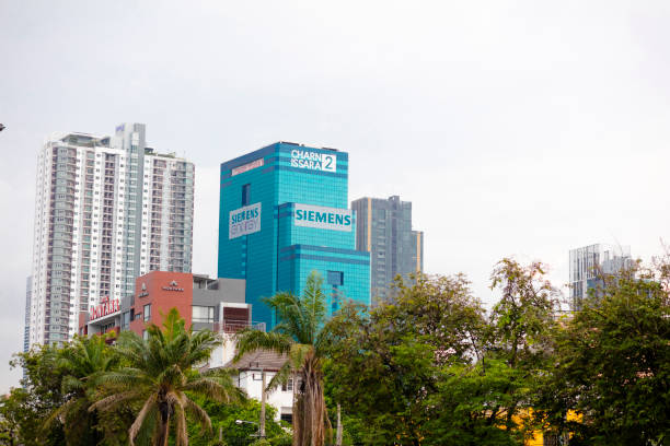 Siemans Chan Issara Tower 2 next other skyscrapers behind trees in Bangkok at Petchaburi Rd, Bang Kapi, seen from Pradit Manutham Road and distance.