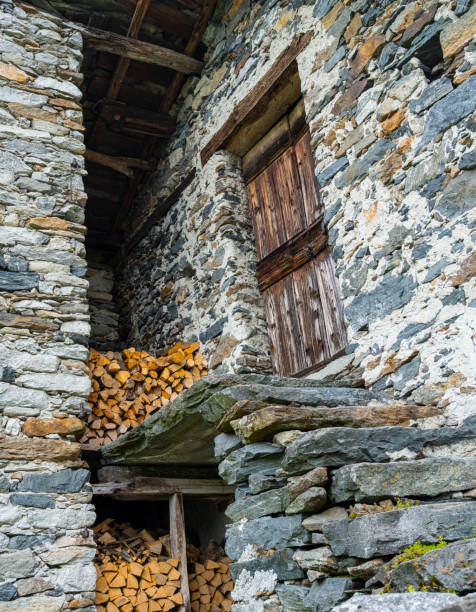 old house made of stone in the mountains with firewood at the entrance