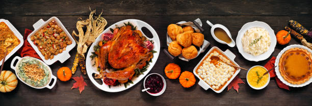 istock Traditional Thanksgiving turkey dinner table scene on a rustic dark wood banner background 2173558247