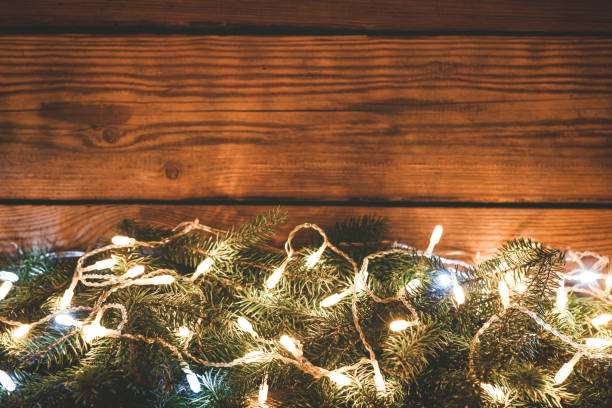 christmas lights on christmas tree on wooden background