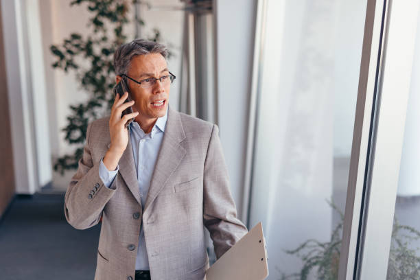 istock Businessman talking on phone and holding documents confidently in the office 2173588155