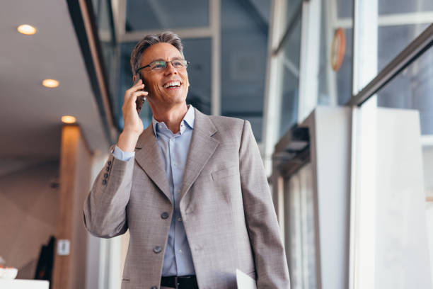Businessman talking on phone and holding documents confidently in the office