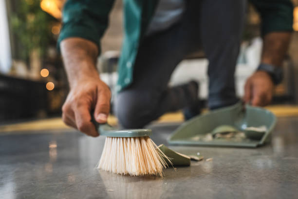 istock Adult man sweep broken vase pieces from a white, shiny floor surface 2173604555