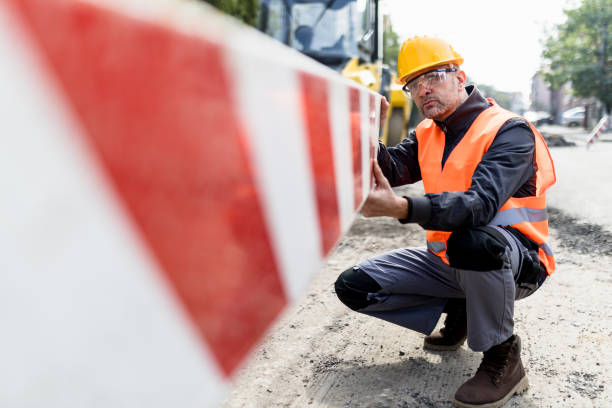 Construction worker inspecting safety barriers on a busy urban construction site during the day