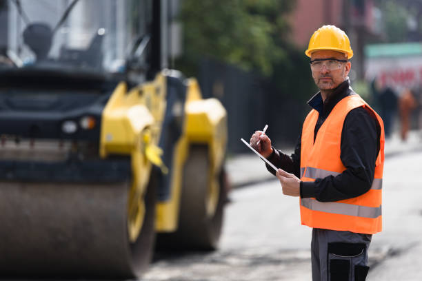 istock Construction worker in safety gear assessing road project during daylight near urban area 2173604995