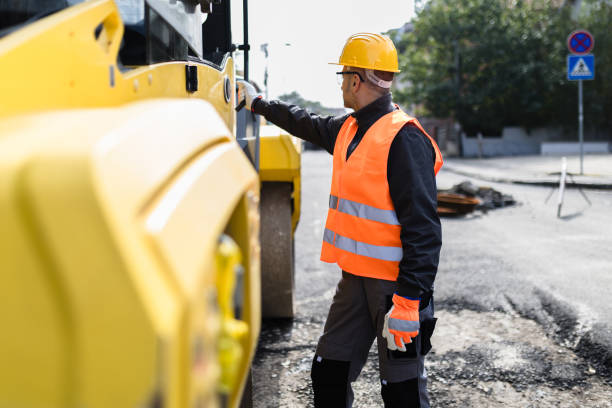 istock Construction worker in safety gear inspecting machinery at a roadwork site during daylight 2173605114