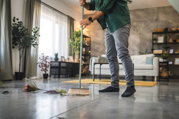 istock Adult man sweep broken vase pieces from a white, shiny floor surface 2173605308