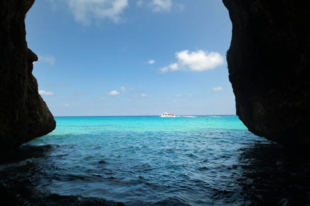 View of boats floating near rocky cliffs and clear blue sea in Favignana, Italy