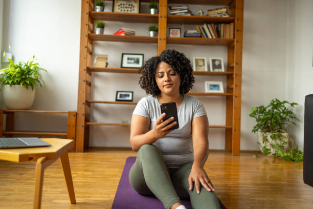 istock Young woman using smartphone on yoga mat at home 2173624314