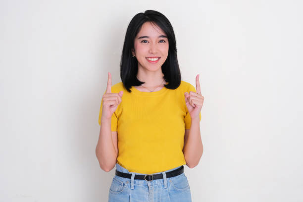 istock Asian woman smiling at the camera with both hands pointing above her 2173624997