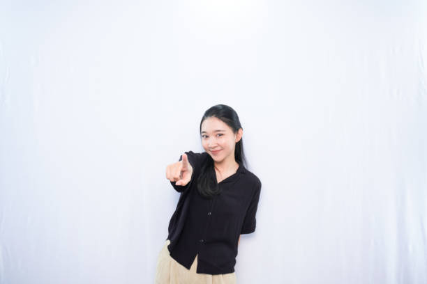 Asian woman in black dress expression pointing to the front side with white background