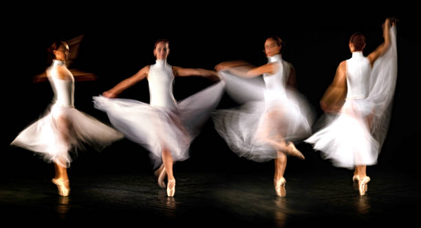 istock Young ballerinas in white skirt dances in studio light.Long exposure. Black Background 2173653489
