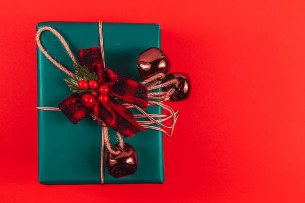 istock Green gift box with bow and bells on red background 2173664161
